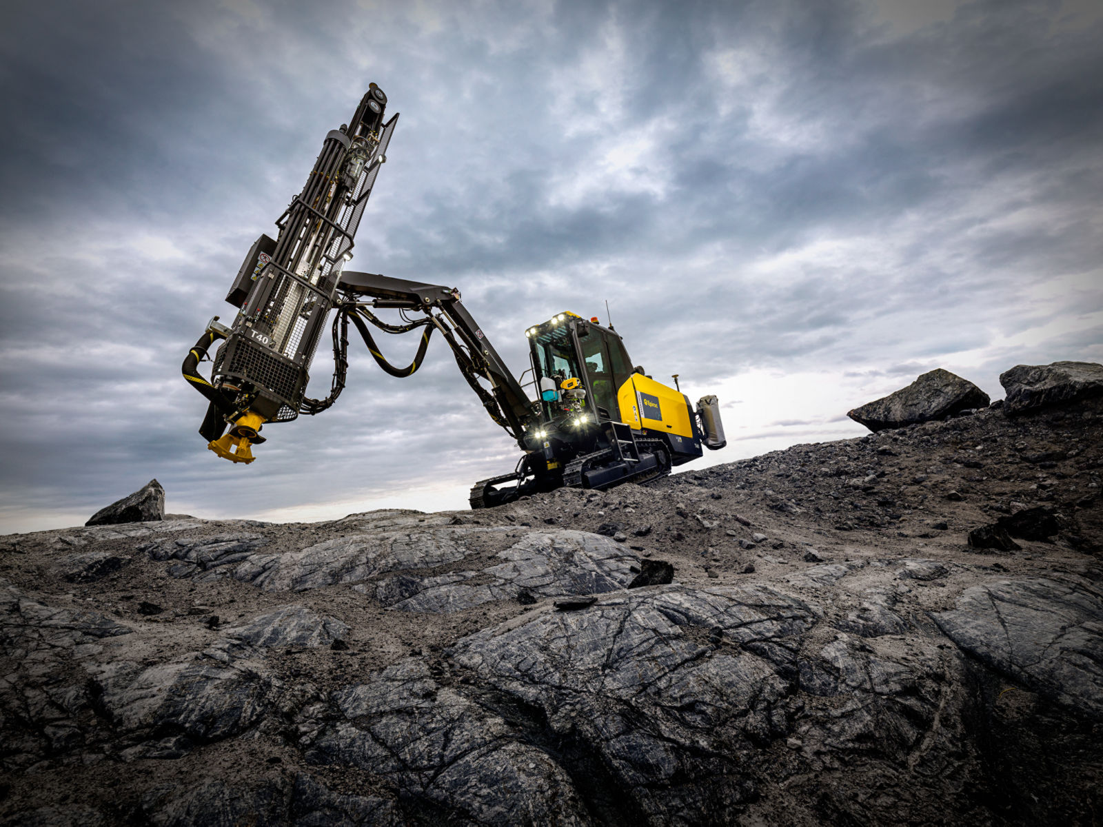 SmartROC T40 working in a quarry dramatically positioned on rocks with a moody sky